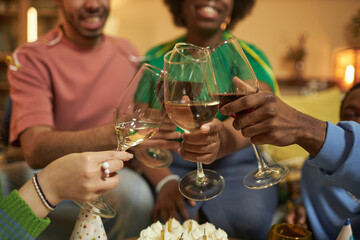 Close up of diverse group of friends clinking wine glasses and toasting during Birthday celebration over cake