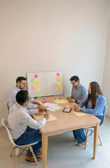 A group of people sitting around a table with sticky notes