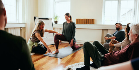 Yoga instructor teaching the crescent lunge pose for her class in a yoga studio