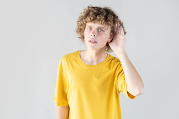 Curious young man with hand to his ear, covertly eavesdropping on conversation while attempting to...