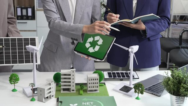 Sustainable business meetings at desks, green energy concepts. People in business suits discussing eco-friendly solutions, solar cells, wind turbines, and promoting net-zero practices.