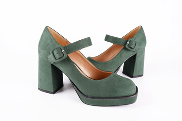 Suede women's green shoes with a strap and buckle on a high thick heel and platform on a white background.Sale of stylish shoes.Workshop for the repair and care of suede and nubuck shoes.