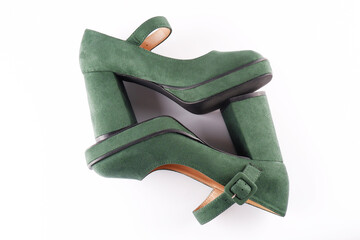 Suede women's green shoes with a strap and buckle on a high thick heel and platform lie on a white background.View from above.Sale of stylish shoes.A workshop for the repair and care of suede shoes.