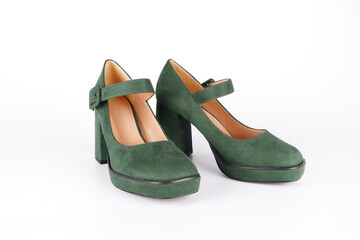 Suede women's green shoes with a strap and buckle on a high thick heel and platform on a white background.Side view.Sale of stylish shoes.Workshop for the repair and care of suede and nubuck shoes.