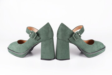 Suede women's green shoes with a strap and buckle on a high thick heel and platform stand heel-to-heel on a white background.Sale of stylish shoes.A workshop for the repair and care of suede shoes.