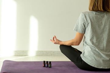 Fitness woman in lotus pose essential oil bottles during yoga training, aromatherapy treatments and meditation. Mental health. 05.07.2021 Tivat