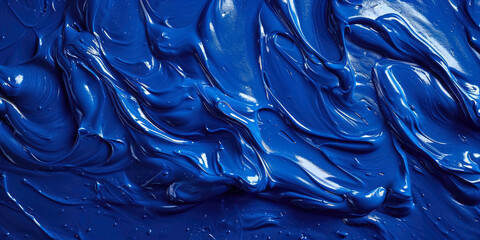 A vibrant burst of royal blue pigment gracefully spread on a glossy surface, forming a mesmerizing and smooth liquid pattern