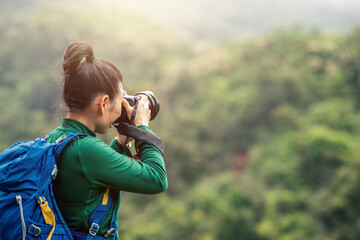 Woman photographer taking photo on spring mountain top - obrazy, fototapety, plakaty