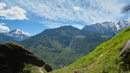 A vast landscape with clear skies, clouds, and snowy mountains.