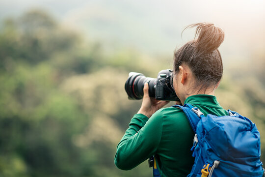 Woman photographer taking photo on spring mountain top