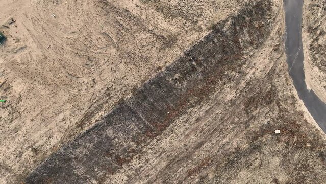 Direct aerial at a patch of dirt, descending toward it.