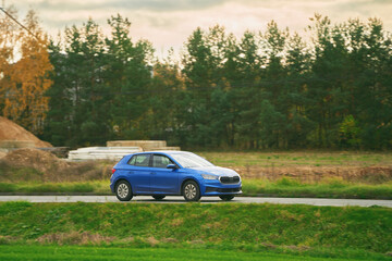 Fototapeta premium Car moving on the highway with blurred natural landscape background. Isolated modern vehicle on the highway during sunset.
