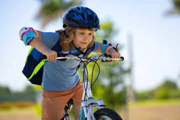 Sporty kid riding bike on a park. Child in safety helmet riding bicycle. Kid learns to ride a bike. Kids on bicycle. Happy child in helmet cycling outdoor. Sports leisure with kids.