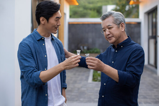 Mid adult man drinking Chinese spirits with his father