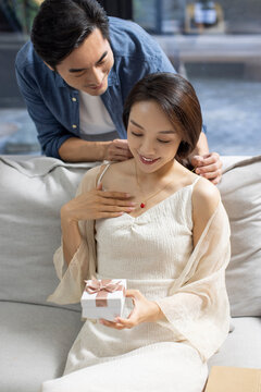 Happy young woman receiving gift from her husband