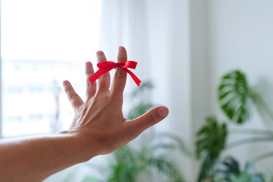 Hand of woman with reminder knot on index finger at home