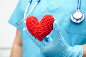 Asian woman doctor holding red heart for health in hospital.