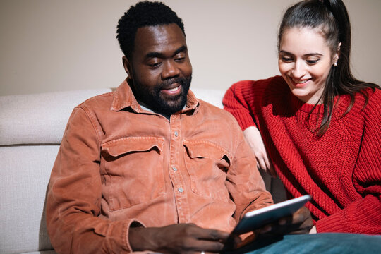 Smiling couple talking and using tablet PC at home