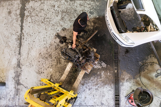 Mechanic disassembling vehicle machine parts at workshop
