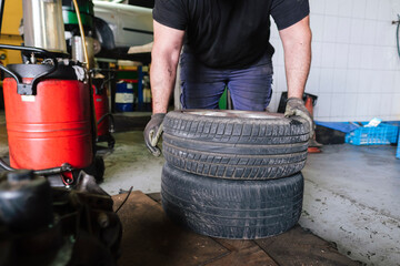 Mechanic placing vehicle tires on floor at workshop