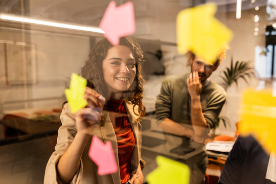 Smiling businesswoman behind glass with colleague at office