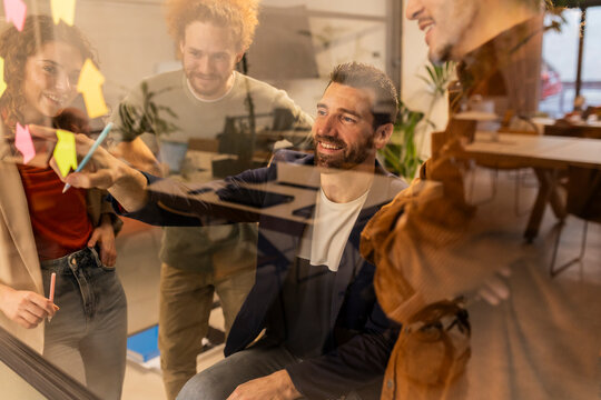Businessman brainstorming colleagues behind glass wall at office