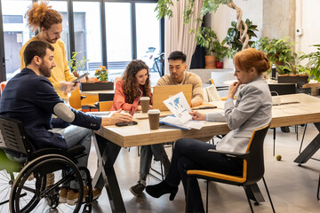 Multiracial business colleagues working together at desk in office