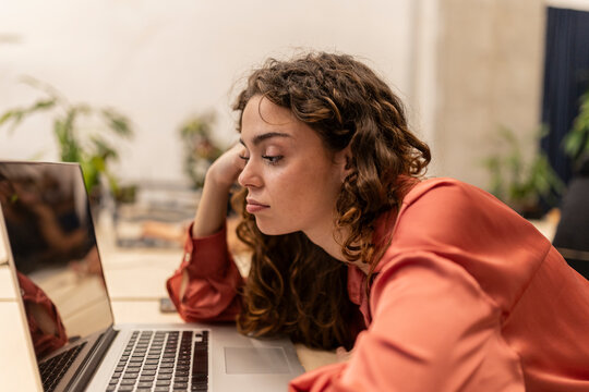 Bored businesswoman looking at laptop on desk at office