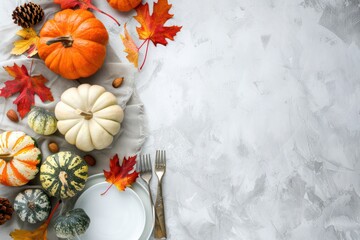 Thanksgiving festive table composition with different colourful pumpkins, autumn leaves, empty plates with cutlery on light grey background table ready for party and celebration. Space for text.