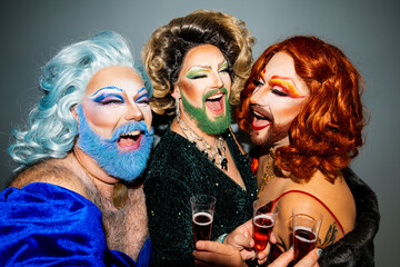 Three drag queens celebrating in style with toasting wine glasses