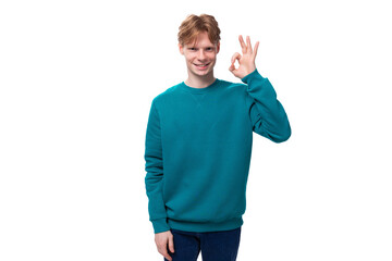 young cheerful smiling caucasian student guy with red hair in a blue sweater