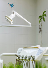 A modern dental chair equipped with tools, positioned under a bright light