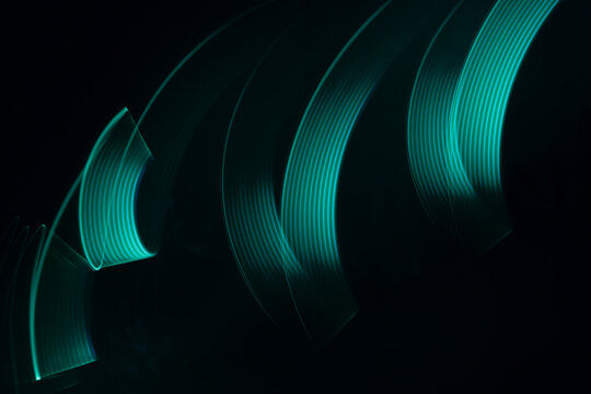 Turquoise green glow neon wave of light with smooth stripes on black background, striped pattern. Abstract background with flowing line in motion, light painting in vapor wave style. - Powered by Adobe