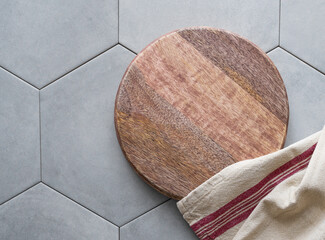 Empty wooden cutting board with napkin on gray ceramic tile in hexagon shape.