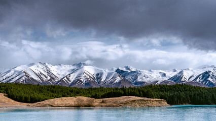 A scenic landscape of New Zealand Southern Alps and Lake Pukaki with blue sky and clouds. South Island, New Zealand. View from Mt Cook Alpine Salmon Shop.
