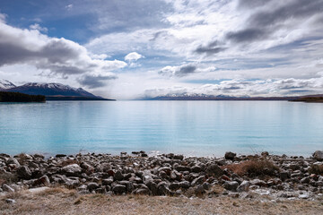 A scenic landscape of New Zealand Southern Alps and Lake Pukaki with blue sky and clouds. South Island, New Zealand. View from Mt Cook Alpine Salmon Shop.