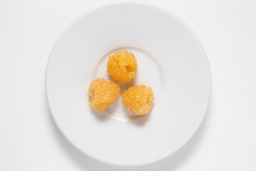 raspberries yellow group on a white plate