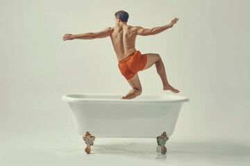A man in orange trunks jumping into a bathtub. Ideal for bathroom or relaxation concepts - obrazy, fototapety, plakaty