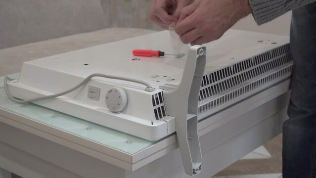 Fasten The leg To An Electric Heater, a man assembles a new electric heater