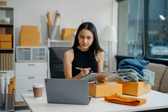 Asian lady blogger showing clothes in front of the camera to recording vlog video live streaming at her shop. 