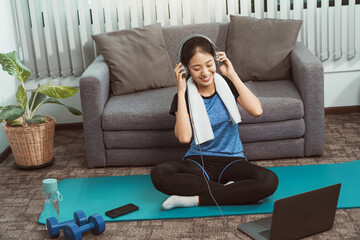 Asian beautiful young woman using laptop and headphones listen music while practicing exercise yoga...