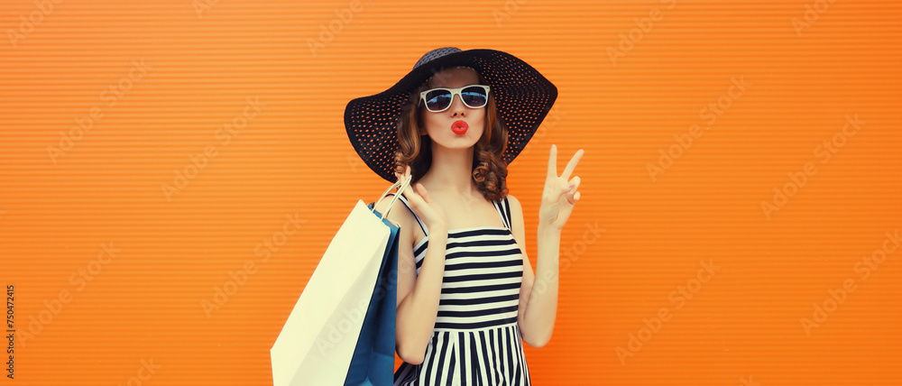 Wall mural beautiful happy woman model with shopping bags in summer black hat, dress on orange background - Wall murals