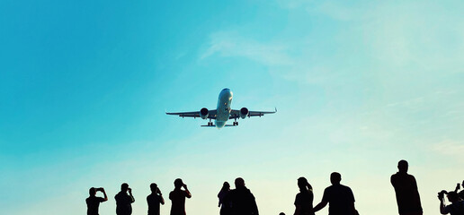 People tourists take pictures a landing passenger airplane flying in blue sky background