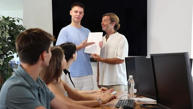  Among students of computer courses, man teacher awards diploma patent and presents document to excellent guy student 