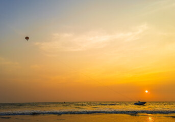 Parasailing extreme sports on beach in sunset background. Paragliding in front of an amazing sunset. A beautiful background of a parasailing parachute on the backdrop a sunset on an evening sky.