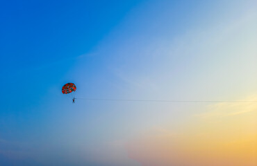 Parasailing extreme sports on beach in blue sky background. Man is parasailing in the blue sky. Paragliding in the clear sky above the sea.
