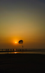 Parasailing extreme sports on beach in sunset background. Paragliding in front of an amazing sunset. A beautiful background of a parasailing parachute on the backdrop a sunset on an evening sky.