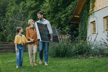 Father mother and daughter walking in garden with solar panel. Solar energy and sustainable...