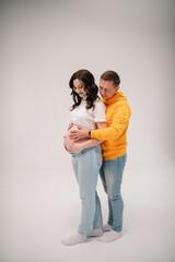 Couple waiting for baby. Family isolated on a white background. Pregnant woman and handsome man hugging tummy at home. Husband embraces belly wife. Nine months. Loving couple smiling embrace together.