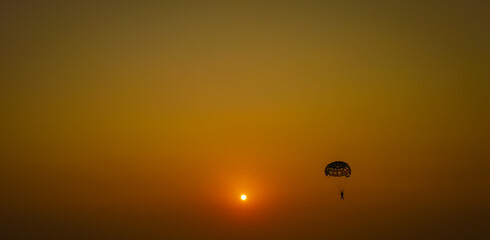 Parasailing extreme sports on beach in sunset background. Paragliding in front of an amazing...